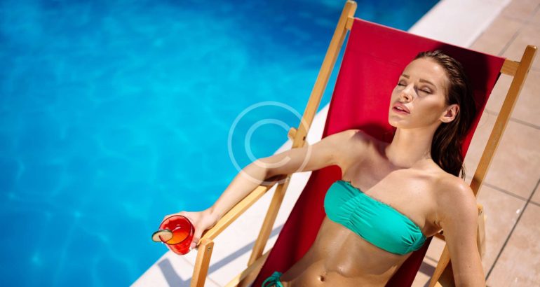 A girl enjoying the sun light beside a fancy pool